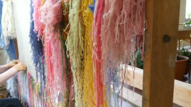 Çok sayıda farklı yün iplikler. El yapımı halı nakışı. Kadınların elleri çok renkli iplikler kullanarak bir desen oluşturur. Nakışlar için çekiç, iplikler için dolgu.