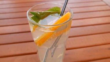 Limonata soğanları bir bardakta portakal, limon, nane dilimleri, ahşap bir masada meyve suyu için kamış, yaz serinletici bir içecek.