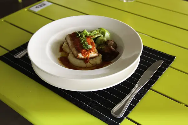 Restaurant menu. Fish fillet with greens. Table setting in a restaurant.