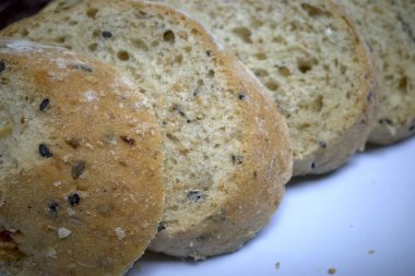 Tam buğday ekmeği, tohumlu, beyaz tabakta kesilmiş, sağlıklı ekmek seçimi..