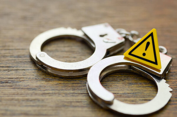 Предостережение: шикарные наручники и ярко-желтый знак, предупреждающий о юридических последствиях преступления.