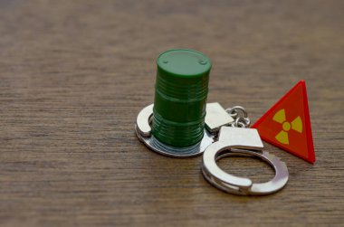 Kelepçe, yeşil fıçı ve radyasyon işaretleri yasadışı yollarla kullanmanın ve tehlikeli atıkları boşaltmanın ağır yasal sonuçlarını simgeliyor..