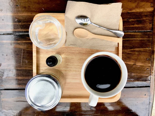 Café preto com colher de chá, água na mesa de madeira — Fotografia de Stock