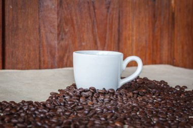 Beyaz fincan kahve ve kahve taneleri çevrili