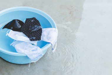 Kumaş maskeler mavi plastik havuzda sırılsıklam olmuş. Su yıkanmaya, durulanmaya, temizlenmeye ve enfeksiyon kapmasını önlemek için tekrar kullanılmaya hazır. Yeni normal bir yaşam sürme kavramı.