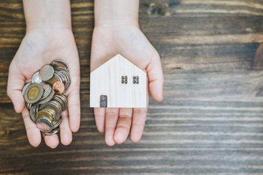 Üst perspektif görünümü veya düz para yatağı ve ev modeli el, konsept ipotek, para tasarrufu, emlak yatırımı ve konut kredisi.