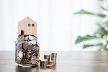 Küplerin üzerine yığılmış ev modeli. Ahşap masa ve ağaç ev dekorasyonu ile karşılanıyor. Kredi, emlak merdiveni, finans, ipotek, gayrimenkul yatırımı ve tasarruf kavramı.