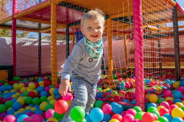 Mutlu küçük çocuk renkli çocuk oyun topları bahçesinde oynuyor. Mutluluk şililik oyun kavramı. Yüksek detaylı stok fotoğrafı