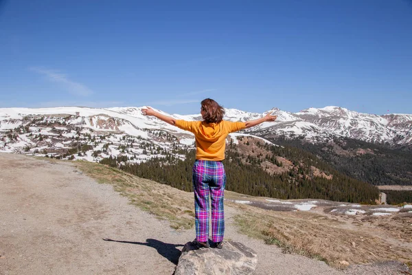 Beautiful woman enjoying nice mountain landscape while traveling. Girl spread her arms on top of mountain. Back view of Woman on the top of snow mountain in sunny day.