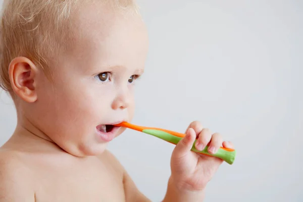 歯の洗浄 歯のブラッシング 小さなかわいい 巻き毛の子供の少年は 光の背景に歯ブラシで歯を磨く 健康管理歯科衛生学 モックアップ コピースペース — ストック写真