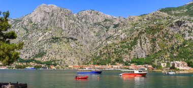 Karadağ 'ın Adriyatik kıyı şeridinde dağları çevreleyen eski Avrupa kenti Kotor, suda teknelerle boka-kotor körfezindeki doğa manzarası.