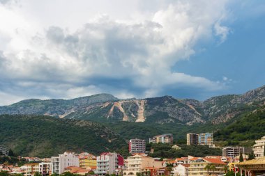Fırtınadan önce etrafı dağlarla çevrili Becici kasabası, Karadağ 'ın Adriyatik kıyı şeridindeki Budva kenti yakınlarındaki dramatik bulutlar. Yaz deniz manzarası.