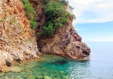 Karadağ 'ın Budva kenti yakınlarındaki Adriyatik kıyı şeridi, kayalıkları ve şeffaf turkuaz sularıyla muhteşem deniz manzarası.