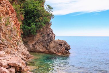 Karadağ 'ın Budva kenti yakınlarındaki Adriyatik kıyı şeridi, kayalıkları ve şeffaf turkuaz sularıyla muhteşem deniz manzarası.
