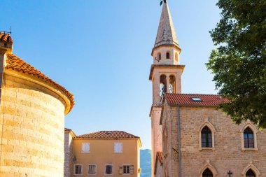 Karadağ 'ın antik Budva kentindeki eski tarihi binalar ve yüksek kilise kulesi cephesi.