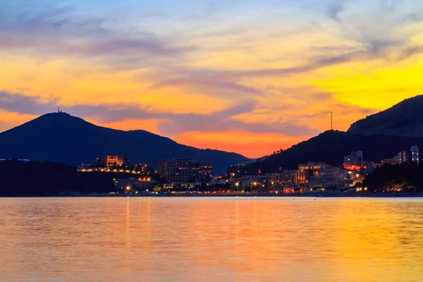 Colorful sunset on Adriatic sea coastline, view to the city in Montenegro, gorgeous seascape.