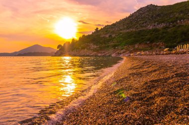 Karadağ 'ın Adriyatik sahil şeridinde altın rengi muhteşem deniz manzaralı gün batımı.