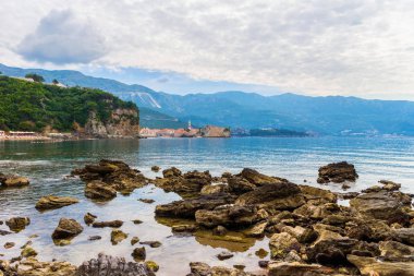 Karadağ 'ın Adriyatik kıyı şeridinde büyük taşlı Mogren plajı ve eski Budva kenti, yaz mevsimi deniz manzarası.