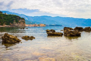 Karadağ 'ın Adriyatik kıyı şeridinde büyük taşlı Mogren plajı ve eski Budva kenti, yaz mevsimi deniz manzarası.