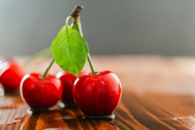 Tahta bir masada yeşil yapraklı taze, kırmızı, ıslak kirazlar..