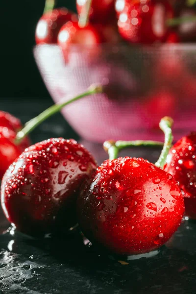 Fresh, wet red cherries on dark background, close-up view.