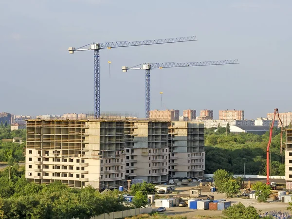 The building site with two new buildings and cranes on a city background.