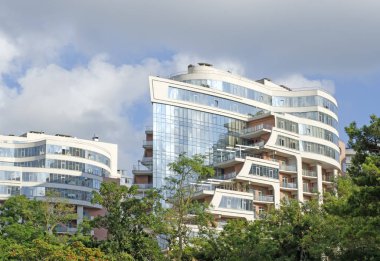 İki yeni yüksek binalar arasında yeşil ağaçlar mavi cam.