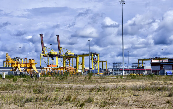 New container terminal. Loading equipment, warehouses, containers close-up against a background of clouds