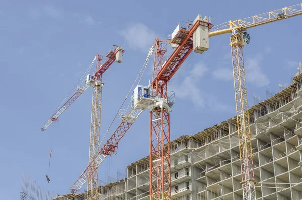 Three construction cranes on the background of a monolithic hous — Stock Photo, Image