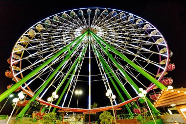 Night view to ferris wheel rotating with motion blur. Colorful lights glowing. Ayia Napa, Cyprus clipart