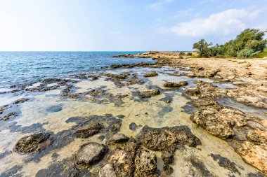 Nissi Beach yaz görünümüne renkli parlak mavi kayalık su ve gökyüzü bulutlu. Negatif kopya alanı, metin için yer. Ayia Napa, Kıbrıs