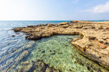 Nissi Beach yaz görünümüne renkli parlak mavi kayalık su ve gökyüzü bulutlu. Negatif kopya alanı, metin için yer. Ayia Napa, Kıbrıs