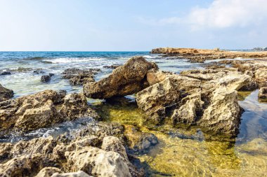 Nissi Beach yaz görünümüne renkli parlak mavi kayalık su ve gökyüzü bulutlu. Negatif kopya alanı, metin için yer. Ayia Napa, Kıbrıs