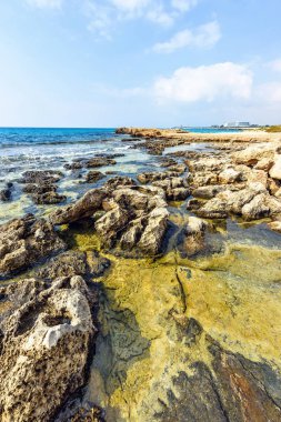 Nissi Beach yaz görünümüne renkli parlak mavi kayalık su ve gökyüzü bulutlu. Negatif kopya alanı, metin için yer. Ayia Napa, Kıbrıs