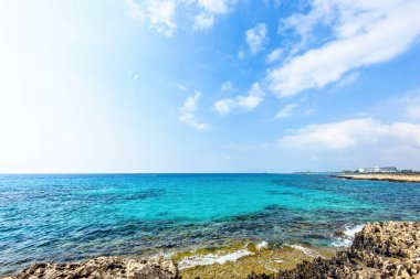 Nissi Beach yaz görünümüne renkli parlak mavi kayalık su ve gökyüzü bulutlu. Negatif kopya alanı, metin için yer. Ayia Napa, Kıbrıs
