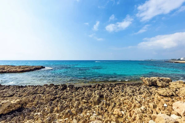 Nissi Beach yaz görünümüne renkli parlak mavi kayalık su ve gökyüzü bulutlu. Negatif kopya alanı, metin için yer. Ayia Napa, Kıbrıs