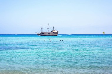 Gün ışığı manzara beachline kişi korsan gemisi arka plan üzerinde seyir izliyor. Negatif kopya alanı, metin için yer. Protaras, Kıbrıs