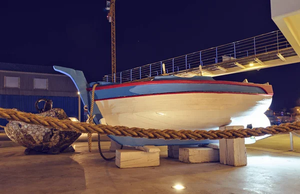 Night view to famous dinghy boat monument near port of city. Bridge on background. Negative copy space, place for text. Limassol, Cyprus