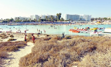 Ayia Napa, Kıbrıs - 18 Eylül 2017: Gün ışığı manzara mavi suda yüzen insanlar için. Otel içinde belgili tanımlık geçmiş. Negatif kopya alanı, metin için yer. Nissi Beach