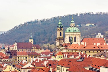 St. Nicholas Katedrali'nin kubbesi ve şehir binaların çatıları. Arka plan ağaç. Bulutlu ve sisli gün. Prague, Çek Cumhuriyeti