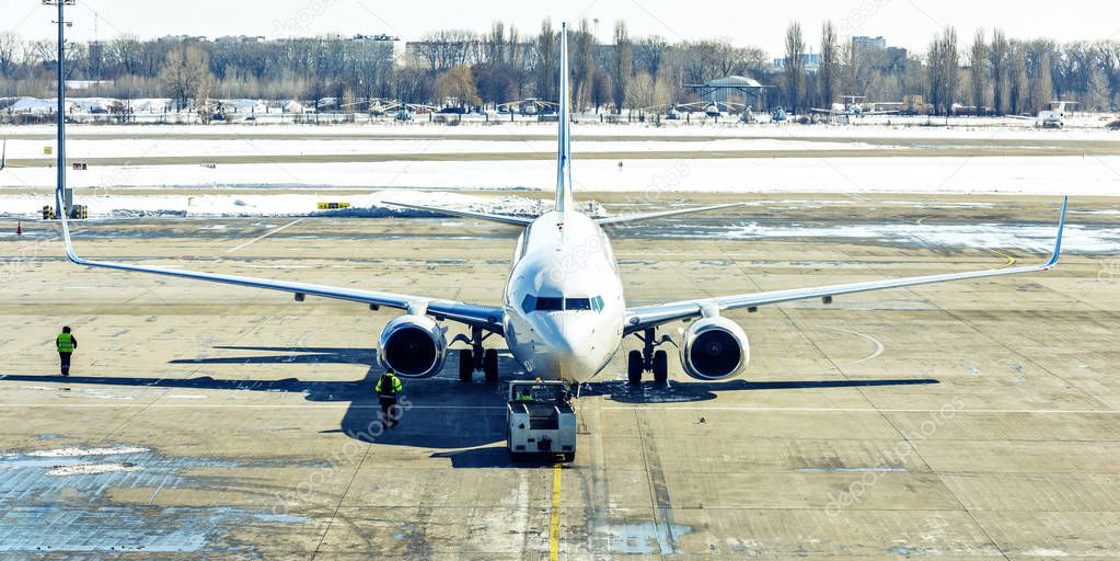 Unbranded plane pushing back from gate with workers controlling front tire direction