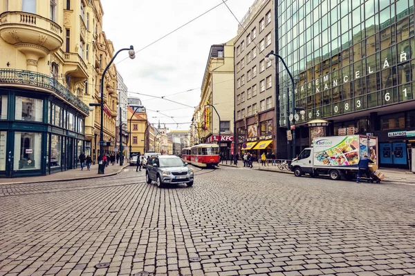 Prague, Çek Cumhuriyeti - 24 Mart 2018: kaldırımda yürüyen insanlar. Arabalar ve eski tramvay yolda sürme. Eski mimari yapılar yansıtan parlak güneş