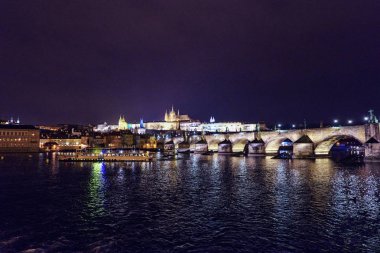 Prag Kalesi ve Charles Köprüsü ile parlayan ve su üzerinde yansıtan ışık gece. Negatif kopya alanı, metin için yer. Çek Cumhuriyeti