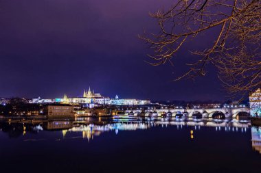 Prag Kalesi ve Charles Köprüsü ile parlayan ve su üzerinde yansıtan ışık gece. Negatif kopya alanı, metin için yer. Çek Cumhuriyeti