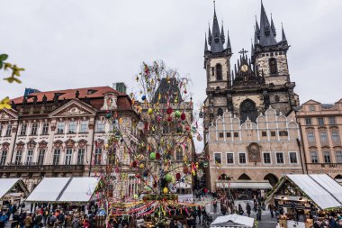 Prague, Çek Cumhuriyeti - 24 Mart 2018: kilise Our Lady Tyn tarihi kent Meydanı'nda önce. Ağaç renkli oyuncaklar ile süslenmiştir. Turistler yerel tezgahları keşfetmek. Dramatik renkler. Bulutlu ve yağmurlu bir gün