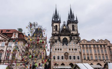 Prague, Çek Cumhuriyeti - 24 Mart 2018: kilise Our Lady Tyn tarihi kent Meydanı'nda önce. Ağaç renkli oyuncaklar ile süslenmiştir. Turistler yerel tezgahları keşfetmek. Dramatik renkler. Bulutlu ve yağmurlu bir gün