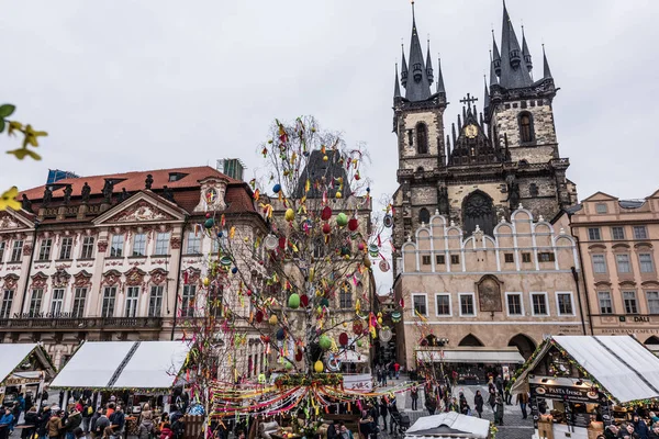 Prague, Çek Cumhuriyeti - 24 Mart 2018: kilise Our Lady Tyn tarihi kent Meydanı'nda önce. Ağaç renkli oyuncaklar ile süslenmiştir. Turistler yerel tezgahları keşfetmek. Dramatik renkler. Bulutlu ve yağmurlu bir gün
