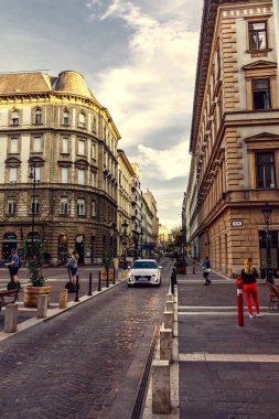 Budapeşte, Macaristan - 10 Nisan 2018: Zrinyi sokak yerel simge ve araba yolda sürme keşfetmek turistlerin gün batımında. Binaların çatılarında yansıtan güneş.