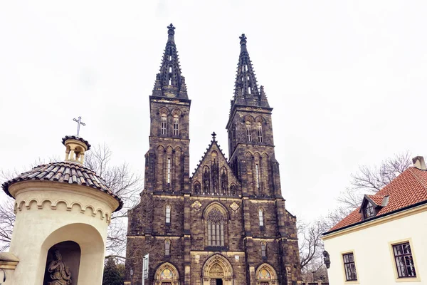 Neo-Gotik Basilica of St. Peter ve St. Paul bulutlu ve yağmurlu bir gün içinde alttan. Kurumuş ağaçları ve taraf diğer binalar. Negatif kopya alanı, metin için yer. Prague, Çek Cumhuriyeti