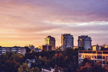 Şehrin yukarısındaki kırmızı günbatımı. Binalarda yansıtan parlak ışık. Bulutlu gökyüzü arka plan üzerinde. Negatif kopya alanı, metin için yer. Kişinev, Moldova
